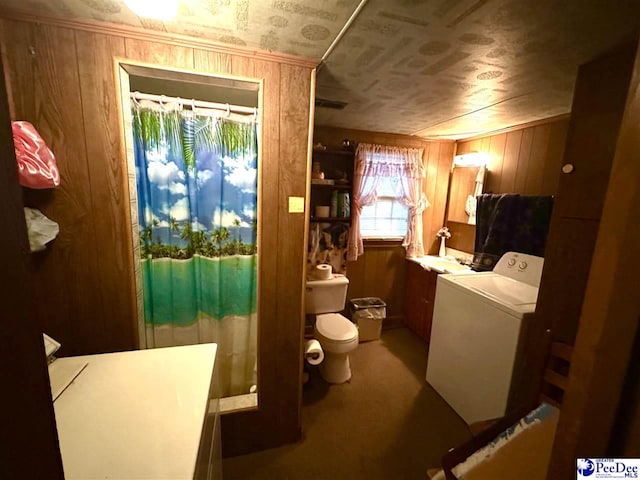 bathroom featuring toilet, wooden walls, and washer / clothes dryer