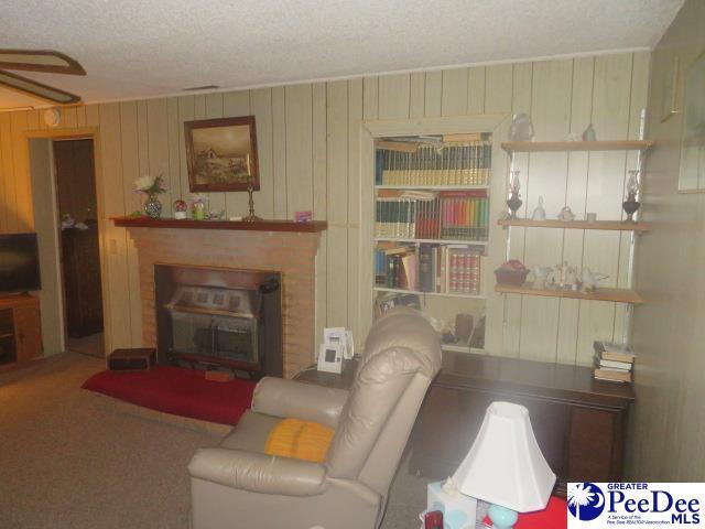 living room featuring a fireplace, wood walls, a textured ceiling, and carpet flooring