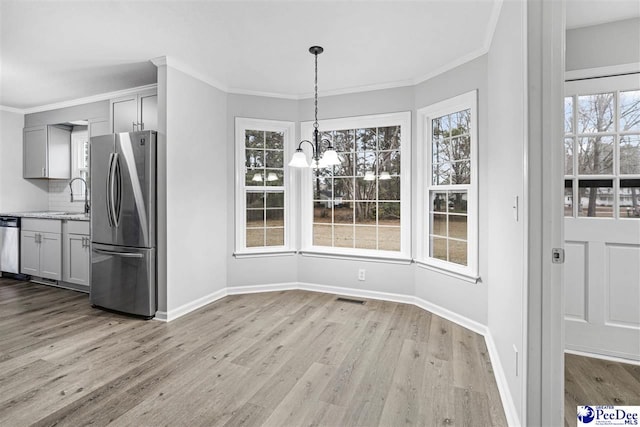 unfurnished dining area featuring crown molding, an inviting chandelier, and light wood-type flooring