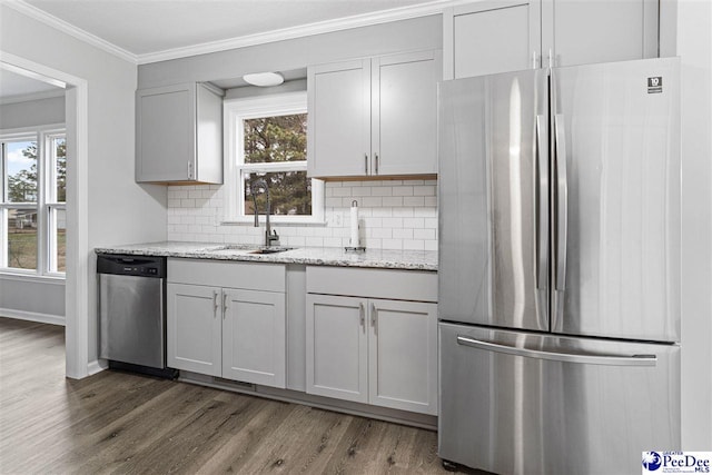 kitchen featuring light stone counters, sink, ornamental molding, and appliances with stainless steel finishes