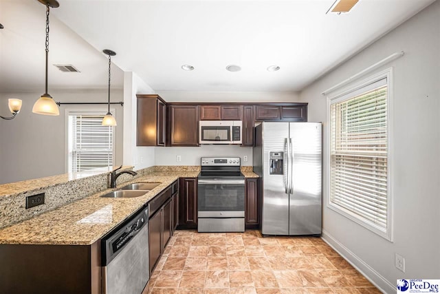2141 Harbour Ln, Florence, SC 29505 - kitchen featuring appliances with stainless steel finishes, dark brown cabinets, light stone counters, a peninsula, and decorative light fixtures
