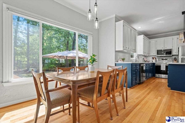 dining room with crown molding, baseboards, and light wood finished floors