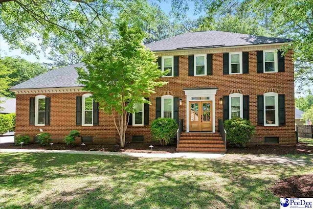 colonial-style house featuring brick siding, crawl space, entry steps, and a front lawn