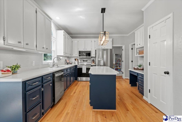 kitchen featuring white cabinets, a sink, blue cabinetry, stainless steel appliances, and a kitchen island