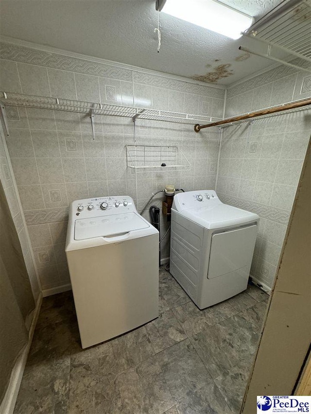 laundry room with washer and dryer and tile walls