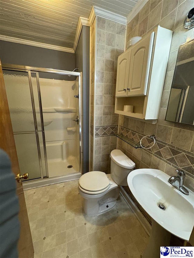 bathroom featuring a shower with door, ornamental molding, sink, and tile walls