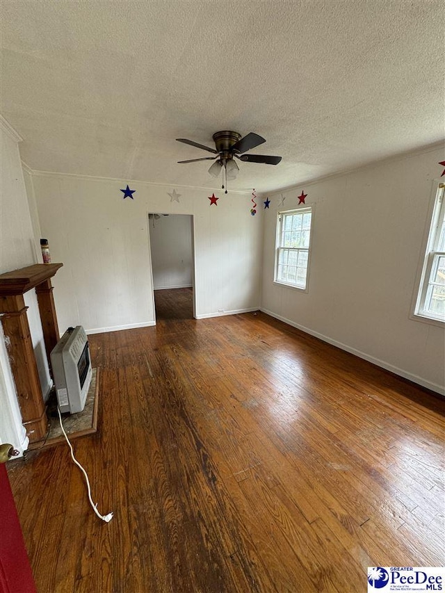 unfurnished living room with ceiling fan, heating unit, a textured ceiling, and dark hardwood / wood-style flooring