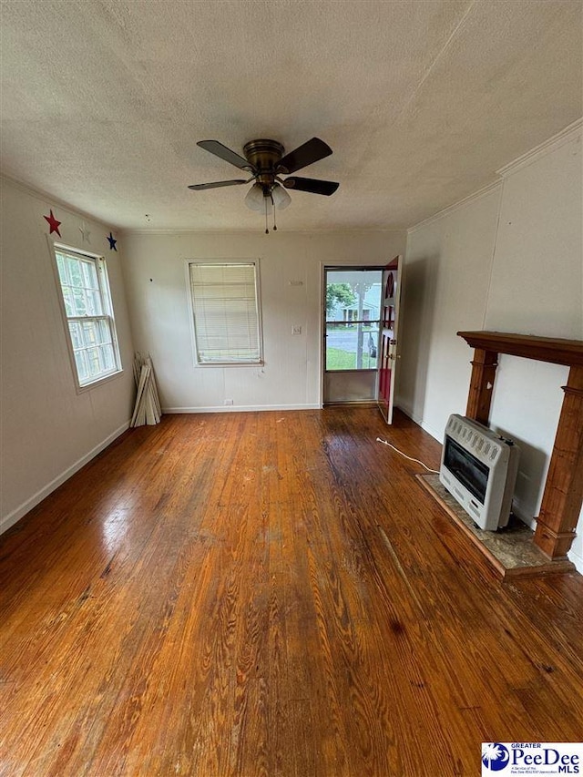 unfurnished living room with heating unit, ceiling fan, wood-type flooring, and a textured ceiling