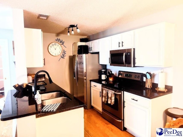 2109UNITG Sanderling, Florence, SC 29501 - kitchen featuring appliances with stainless steel finishes, a sink, white cabinets, light wood-style flooring, and a textured ceiling