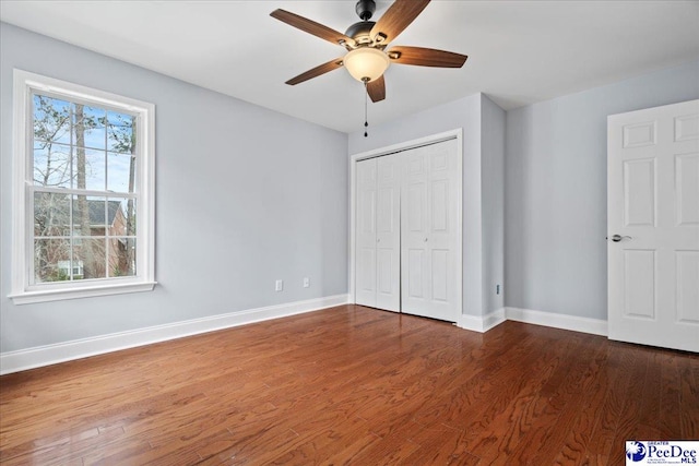 unfurnished bedroom featuring a closet, ceiling fan, baseboards, and wood finished floors