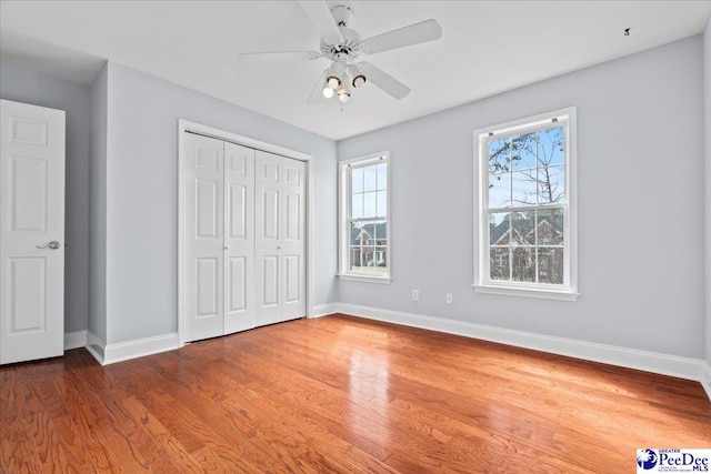 unfurnished bedroom featuring ceiling fan, a closet, baseboards, and wood finished floors