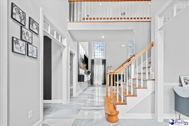 foyer entrance featuring marble finish floor, baseboards, stairs, and a towering ceiling