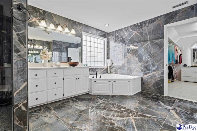 bathroom featuring visible vents, vanity, a garden tub, marble finish floor, and tile walls