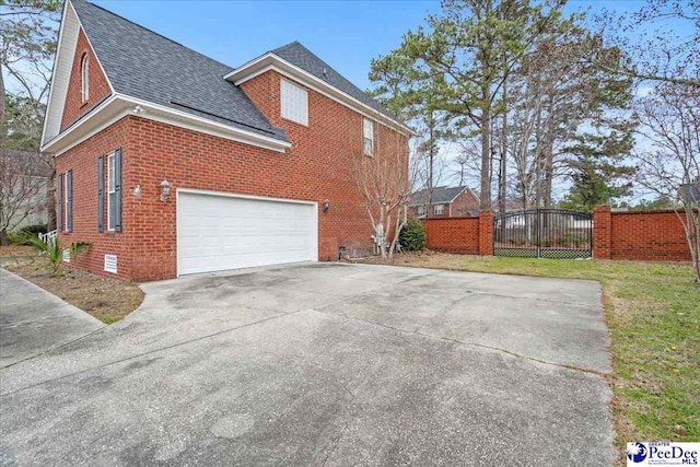 view of side of home with driveway, roof with shingles, a garage, crawl space, and brick siding