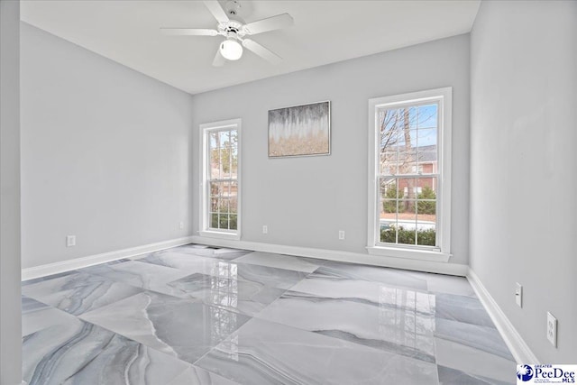 empty room featuring baseboards, marble finish floor, and ceiling fan