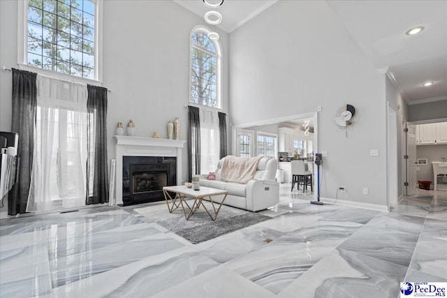 living area featuring a fireplace with flush hearth, marble finish floor, a towering ceiling, and ornamental molding