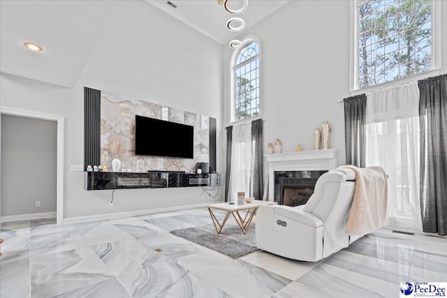 living room featuring a glass covered fireplace, marble finish floor, high vaulted ceiling, and plenty of natural light