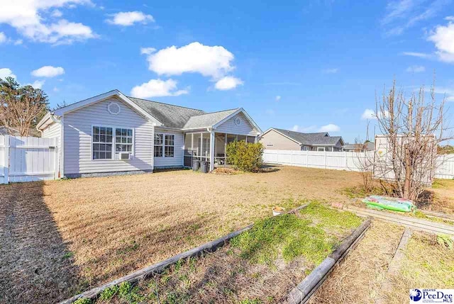 view of front of home featuring a sunroom, a fenced backyard, and a front lawn