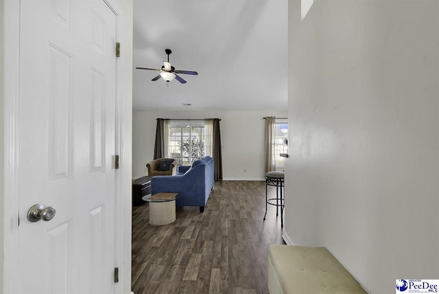 corridor featuring baseboards and dark wood finished floors