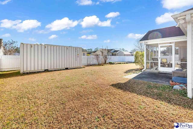 view of yard with an outbuilding, a sunroom, and a fenced backyard