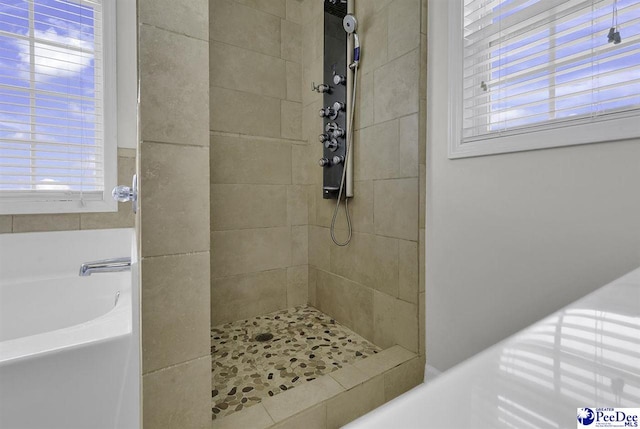 bathroom with a wealth of natural light, tiled shower, and a garden tub