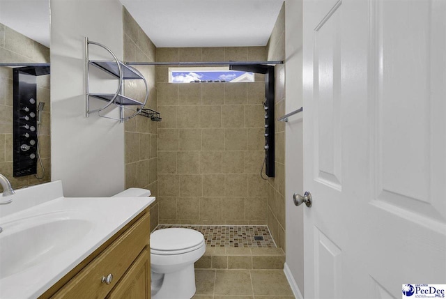 bathroom featuring toilet, a stall shower, tile patterned flooring, and vanity