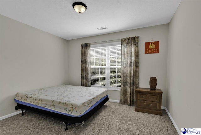 carpeted bedroom featuring visible vents, baseboards, and a textured ceiling