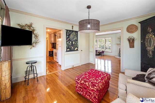 living room with crown molding, light wood finished floors, and baseboards