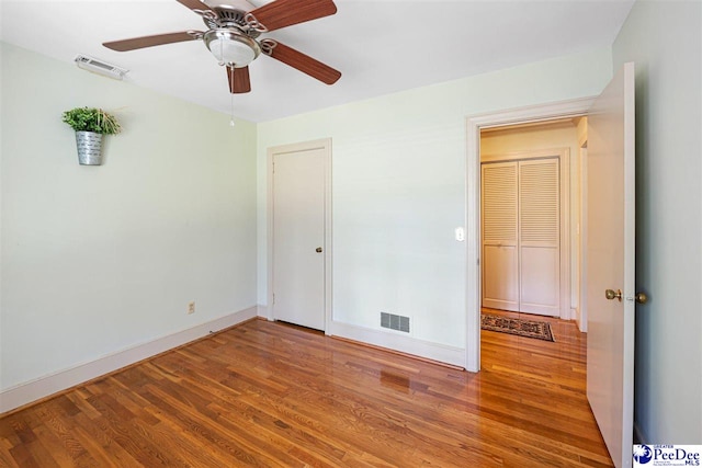 unfurnished bedroom featuring wood finished floors, baseboards, and a ceiling fan