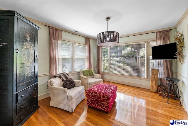 sitting room featuring wood finished floors, baseboards, and crown molding