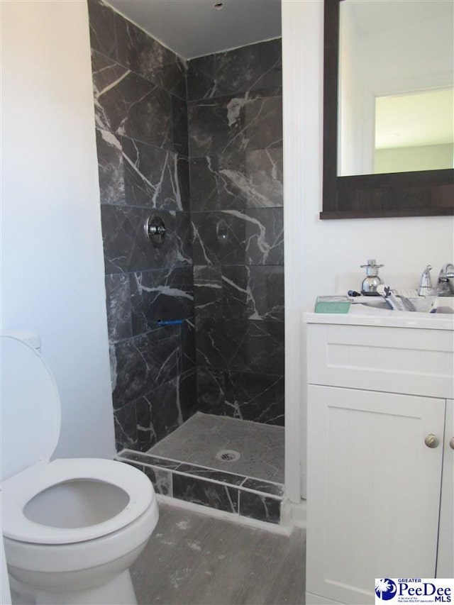 bathroom with vanity, toilet, and tiled shower