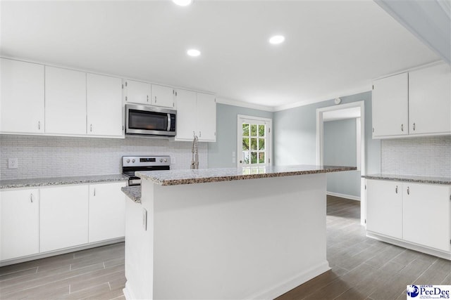 kitchen with a kitchen island, light stone countertops, appliances with stainless steel finishes, and white cabinets