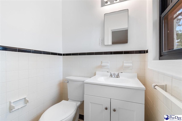 bathroom featuring vanity, toilet, and tile walls