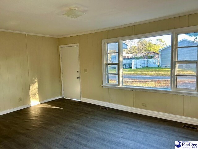 spare room with ornamental molding and dark wood-type flooring