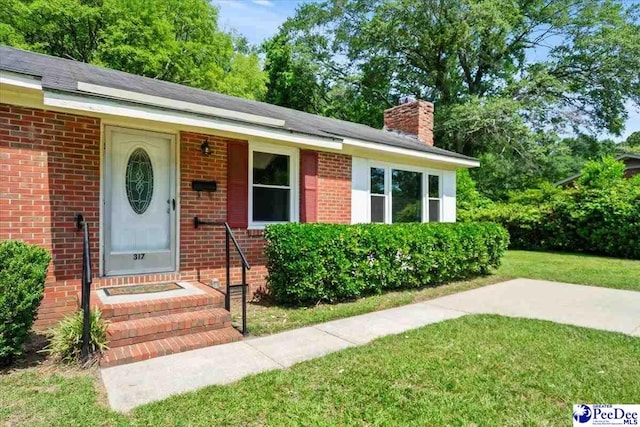 317 Thomas St, Bennettsville, SC 29512 - view of front of house with a front lawn, a chimney, and brick siding
