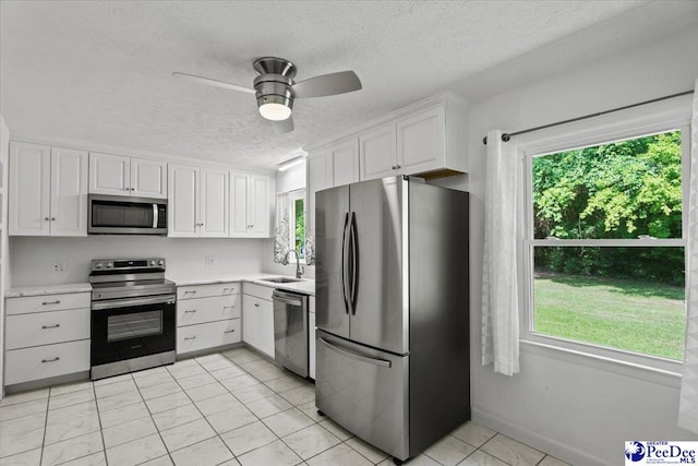 317 Thomas St, Bennettsville, SC 29512 - kitchen with stainless steel appliances, a textured ceiling, healthy amount of natural light, light countertops, and white cabinets