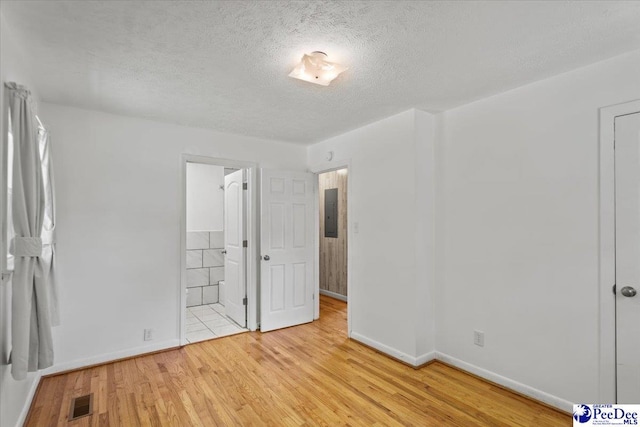 317 Thomas St, Bennettsville, SC 29512 - unfurnished bedroom with light wood-style floors, a textured ceiling, electric panel, and ensuite bath