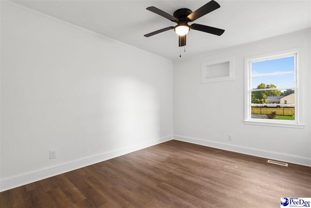 unfurnished room featuring dark wood finished floors, visible vents, ceiling fan, and baseboards