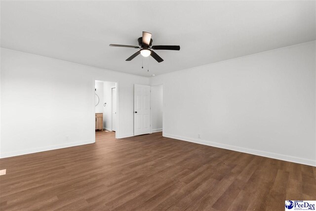 unfurnished bedroom featuring connected bathroom, dark wood-style floors, baseboards, and ceiling fan