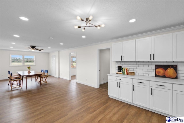 kitchen featuring tasteful backsplash, crown molding, light countertops, wood finished floors, and white cabinets