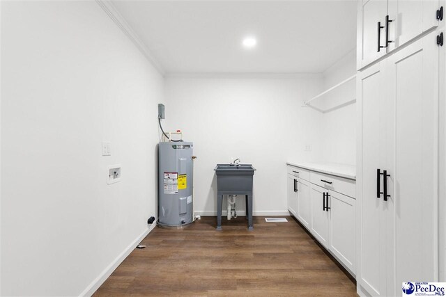 laundry room featuring baseboards, dark wood finished floors, water heater, washer hookup, and crown molding