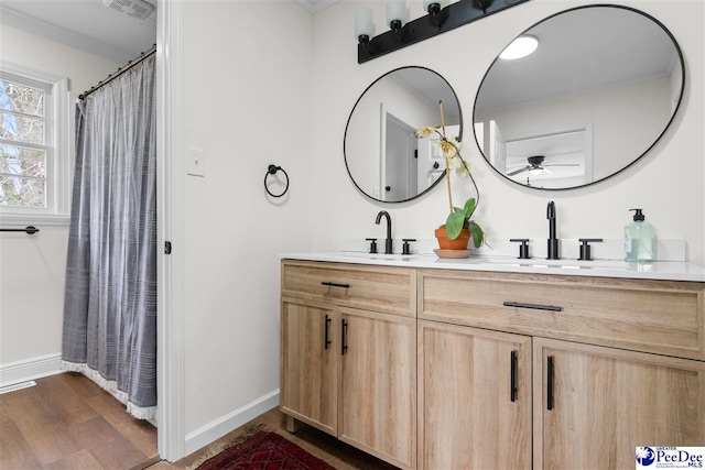 bathroom with double vanity, wood finished floors, visible vents, and a sink