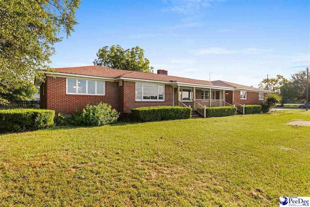 ranch-style house with brick siding, a chimney, and a front yard