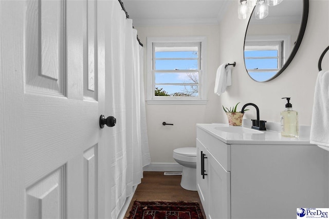 bathroom with baseboards, toilet, ornamental molding, wood finished floors, and vanity