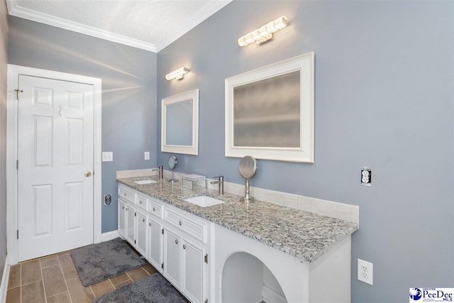 full bath with crown molding, double vanity, baseboards, and a sink