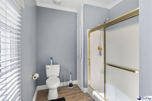 bathroom with a shower stall, toilet, crown molding, and wood finish floors