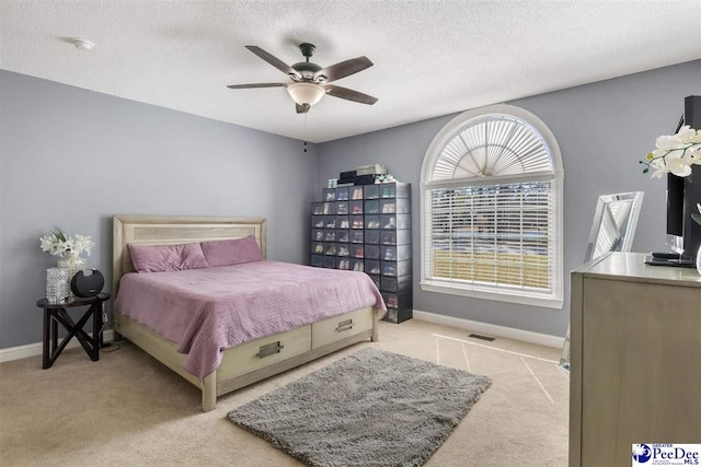 carpeted bedroom with a ceiling fan, visible vents, baseboards, and a textured ceiling