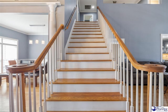 stairway with visible vents, crown molding, and wood finished floors