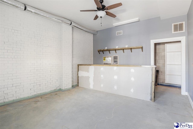 basement featuring visible vents, brick wall, and a ceiling fan