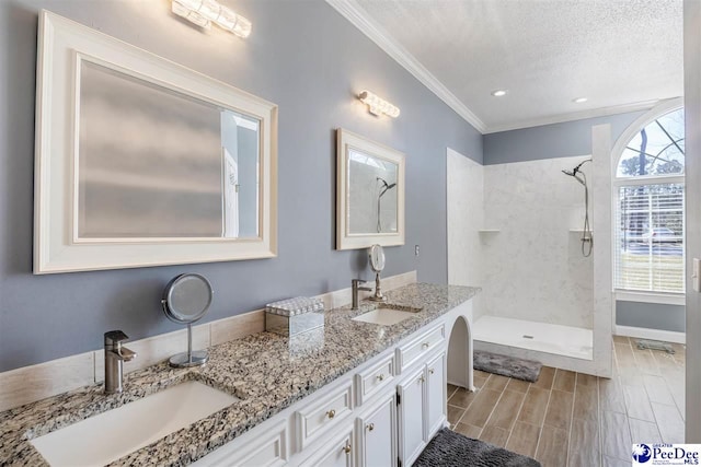 full bathroom featuring a textured ceiling, tiled shower, wood finish floors, and a sink